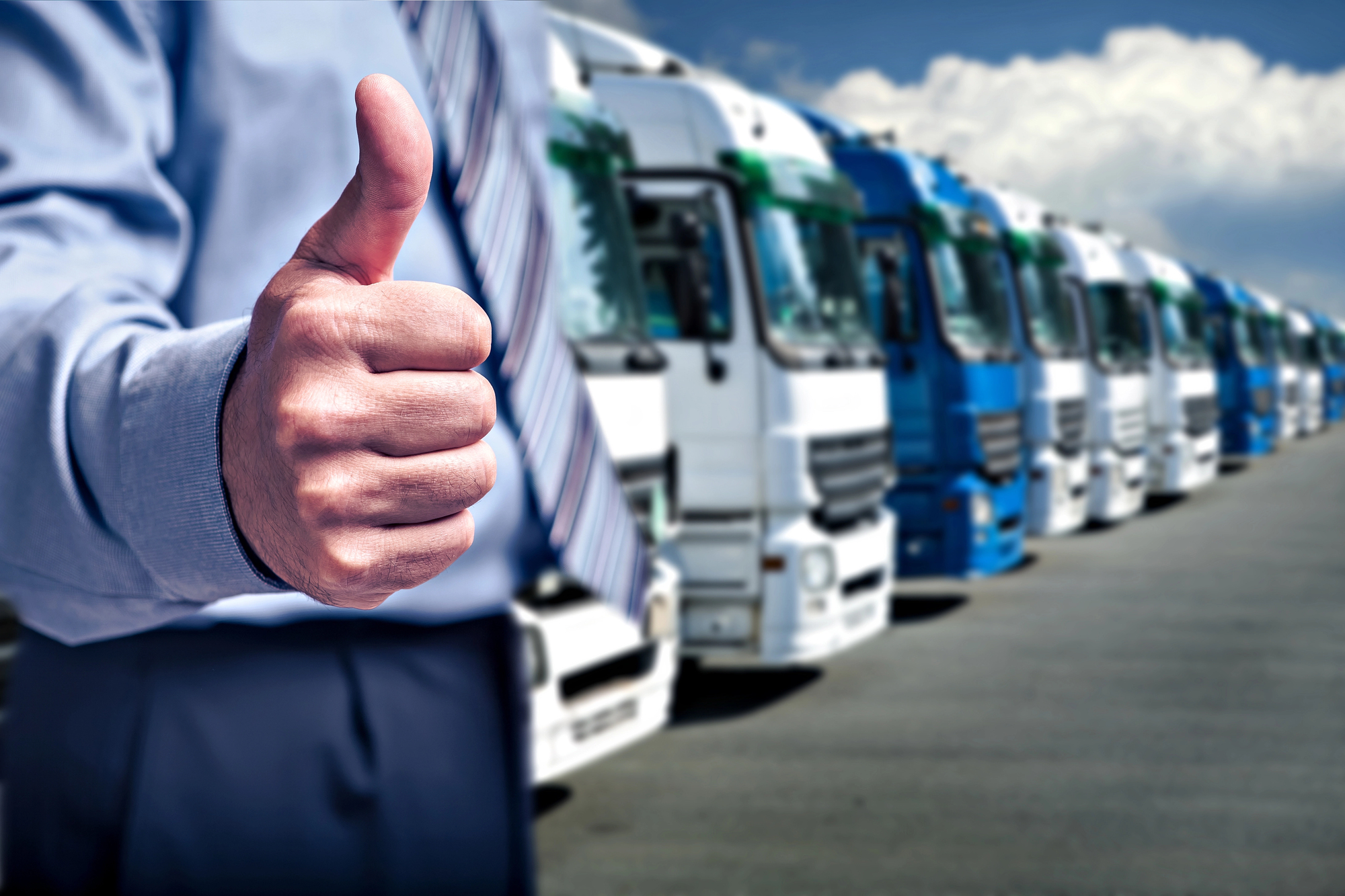 Daumen hoch vor einer LKW-Flotte zur Tachographenpflicht in Österreich